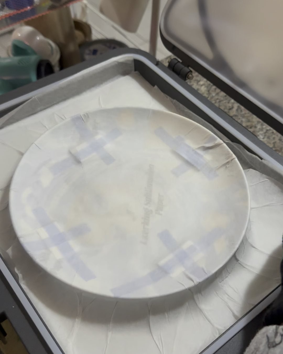 Plato con el papel de transferencia sujeto con cinta en la prensa de calor