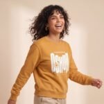 Modelo sonriendo con la sudadera de Oshún amarilla