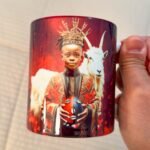 Taza de Eleguá niño con su corona y un chivo, asa e interior rojo