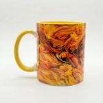 Taza de Oshún envuelta en flores naranjas y doradas, asa e interior amarillo
